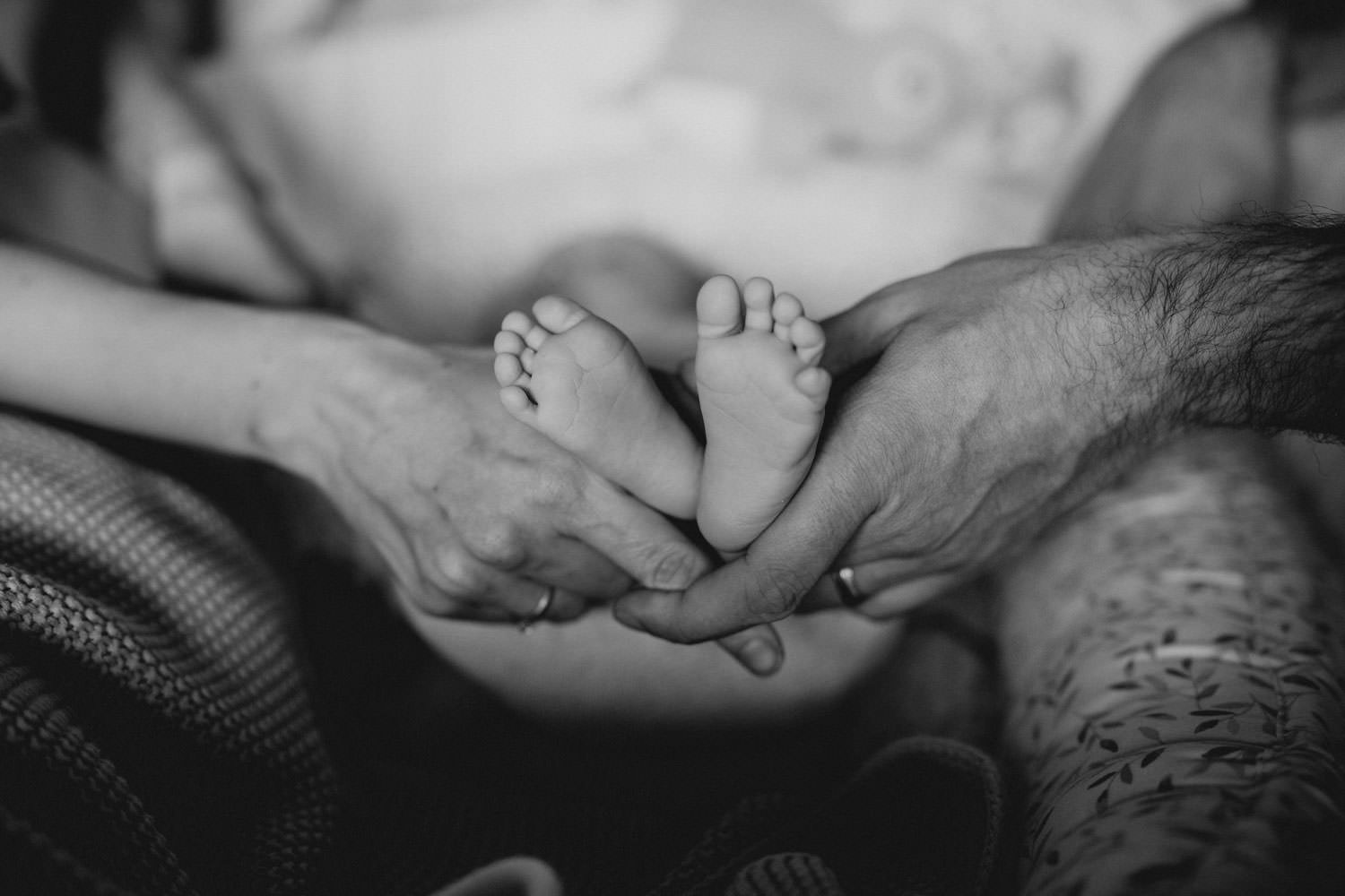 Babyfüße werden von Mamas und Papas Händen gehalten bei einem Fotoshooting von Patricia Hamann