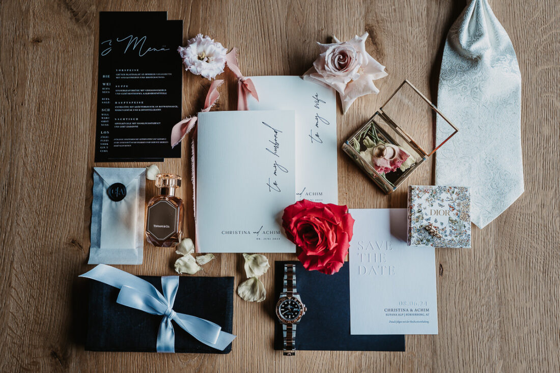 Hochzeitseinladungen, Schmuck, Krawatte, Hochzeitsdetails und Blumen zusammengelegt auf einem Holzuntergrund - Hochzeitsfotograf Patricia Hamann