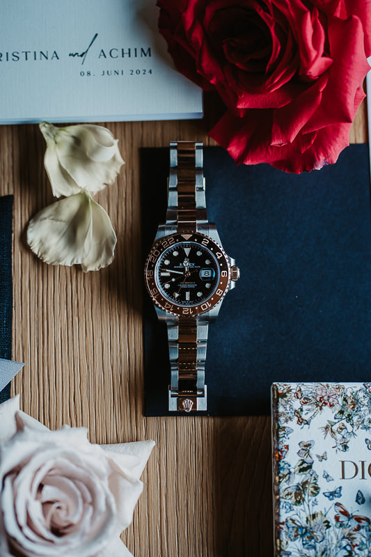 Rolex in der Mitte von Hochzeitseinladung, Blumen und Schmuck - Hochzeitsfotograf Patricia Hamann