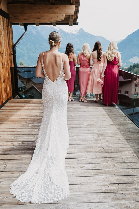 Die Braut geht auf ihre Trauzeuginnen zu, die mit dem Rücken zu ihr stehen und auf die Berge blicken - Hochzeitsfotograf Patricia Hamann