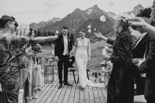 Brautpaar verlässt die Trauung unter fliegenden Blütenblättern auf der Rufana Alp – Hochzeitsfotograf Tirol Patricia Hamann