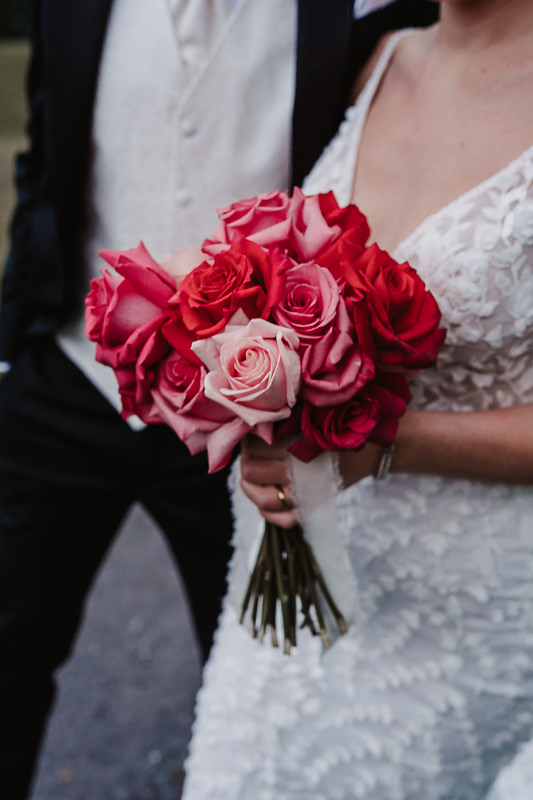 Detailfoto des Brautstraußes mit roten und rosafarbenen Rosen – Hochzeit auf der Rufana Alp in Tirol, fotografiert von Patricia Hamann