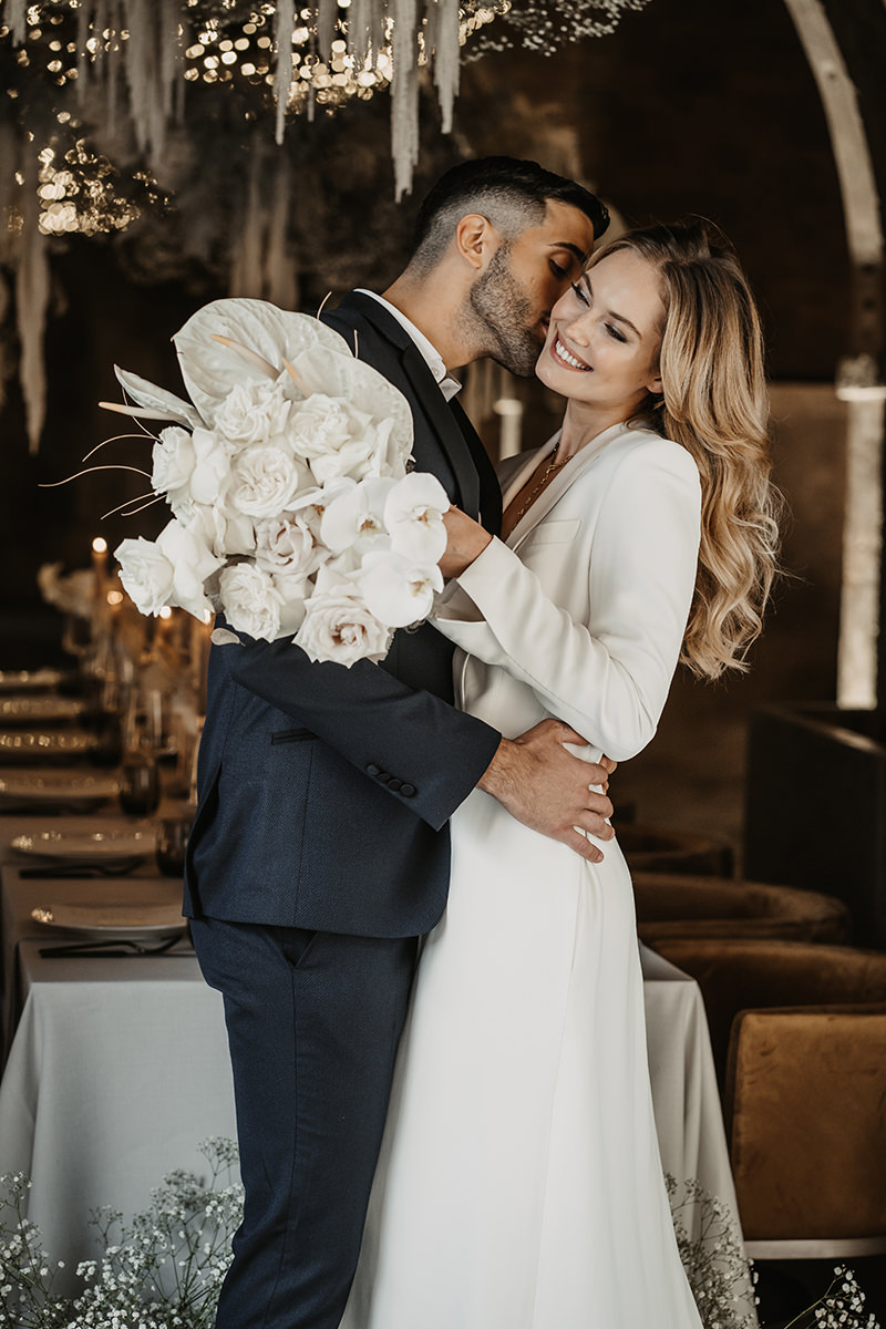 Umarmendes Brautpaar steht vor dem dekoriertem Tisch einer Hochzeitslocation in der Toskana
