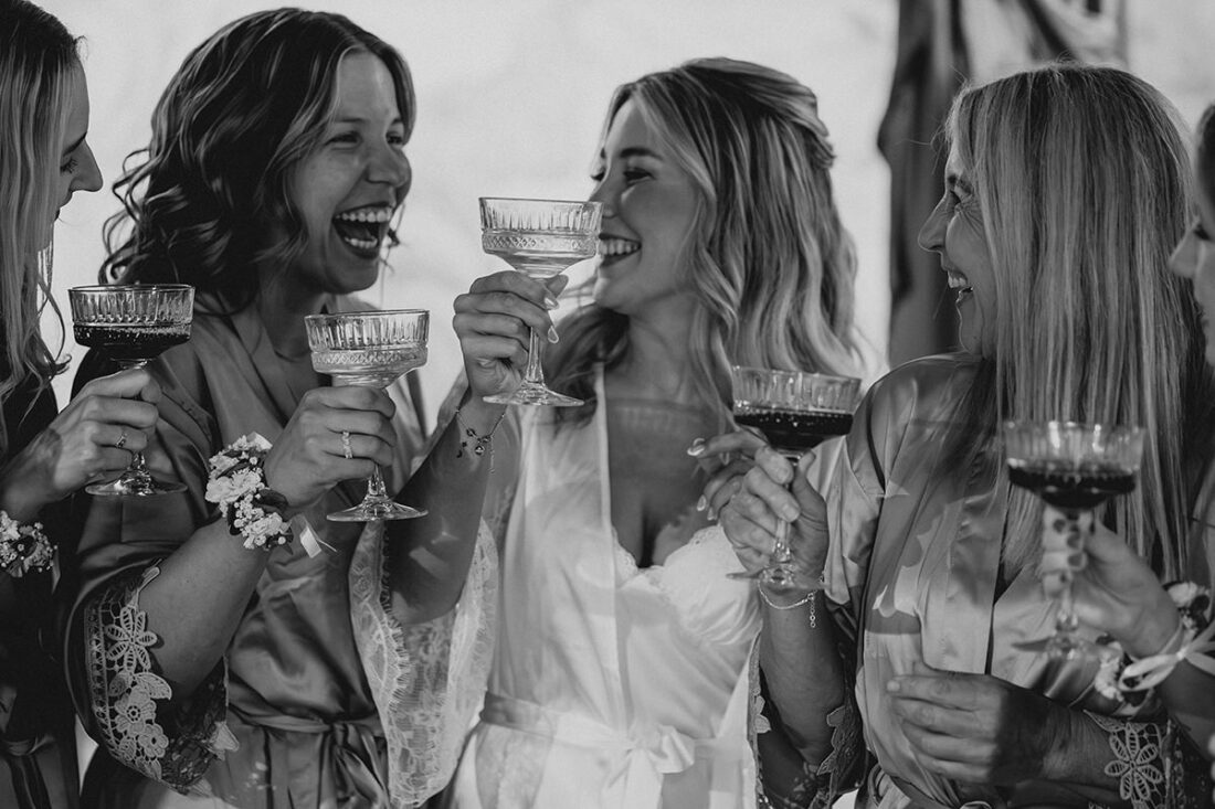 Braut stoßt mit ihren Freundinnen beim Getting Ready ihrer Hochzeit mit Champagner an.