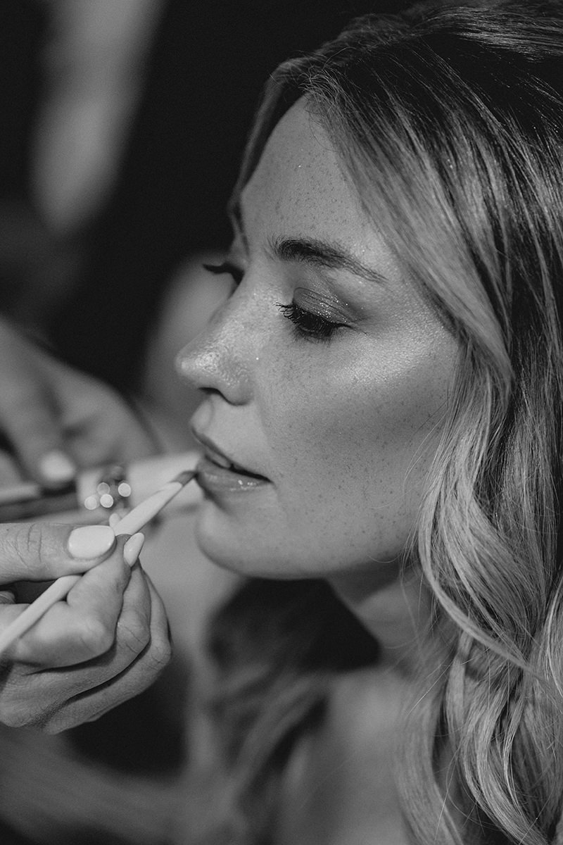 Portraitaufnahme der Braut an ihrer Hochzeit wie sie von Stylistin den Lippenstift aufgetragen bekommt - Hochzeitsfootgraf Patricia Hamann