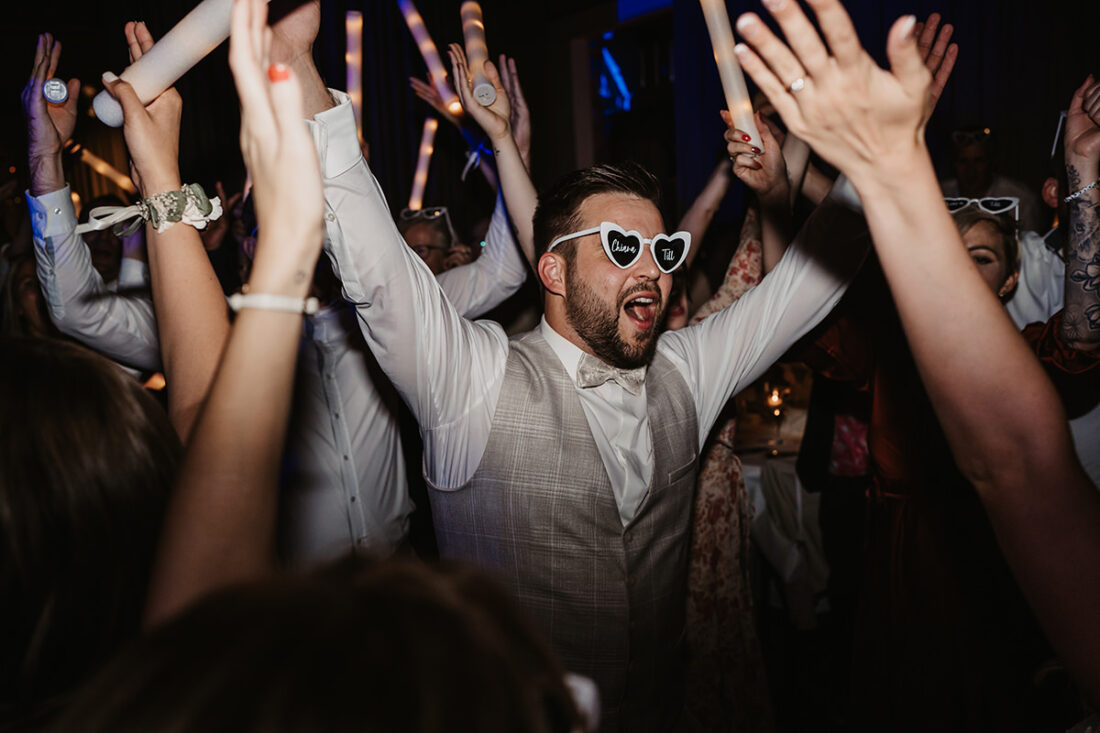 Feiernder Bräutigam tanzt und hebt Hände in die Luft