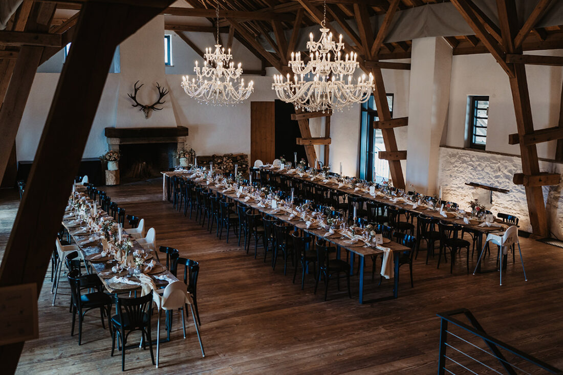 Festlich geschmückter Saal mit langen Tafeln und Kronleuchtern bei einer Hochzeit auf dem Hofgut Maisenburg - Hochzeitsfotograf Patricia Hamann