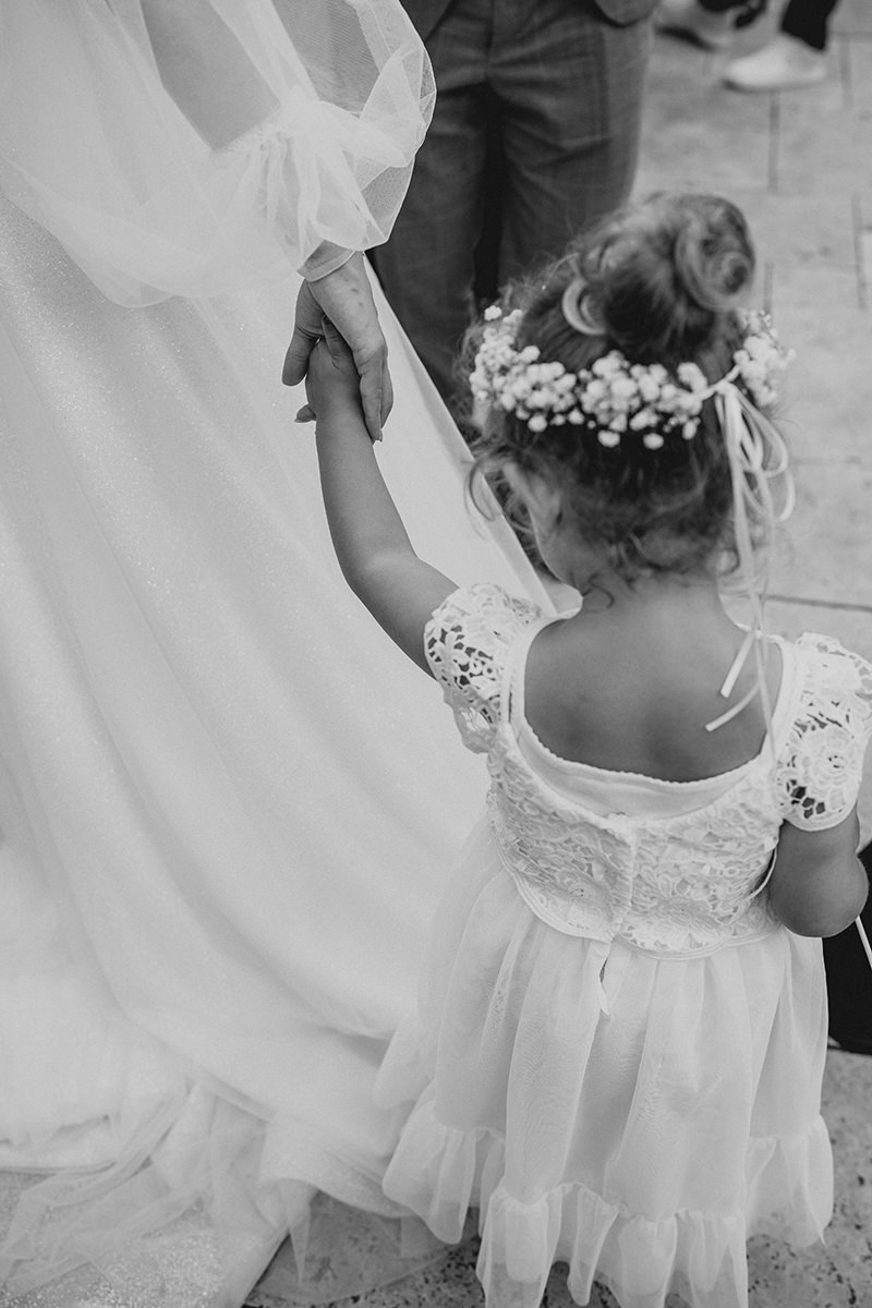 Braut nimmt Blumenmädhcen an die Hand