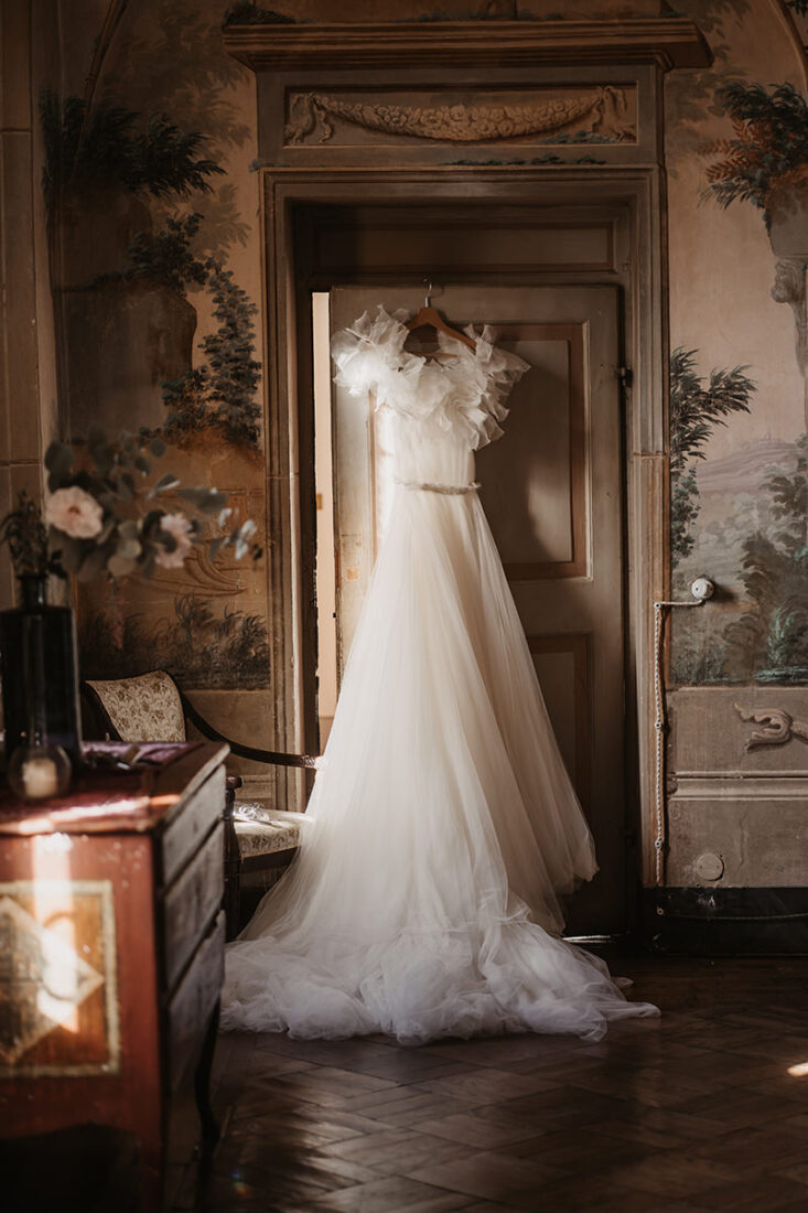 Das Brautkleid von Kaviar Gauche hängt beim Getting Ready an der Türe einer toskanischen Villa - fotografiert von Patricia Hamann