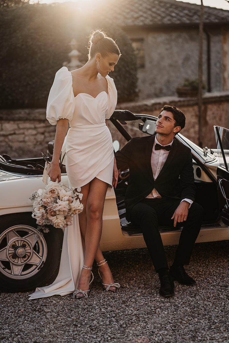 Braut lehnt sich an Oldtimer Cabrio, während Bräutigam lässig mit offener Türe auf dem Beifahrersitz sitzt - Hochzeitsfotograf Patricia Hamann