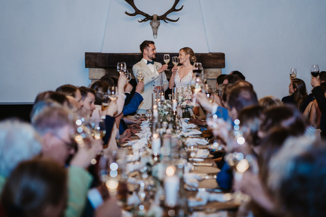 Braut und Bräutigam stoßen bei ihrer Hochzeit auf der Maisenburg bei Ulm mit Gästen an – festgehalten von Patricia Hamann, Hochzeitsfotografin aus Ulm