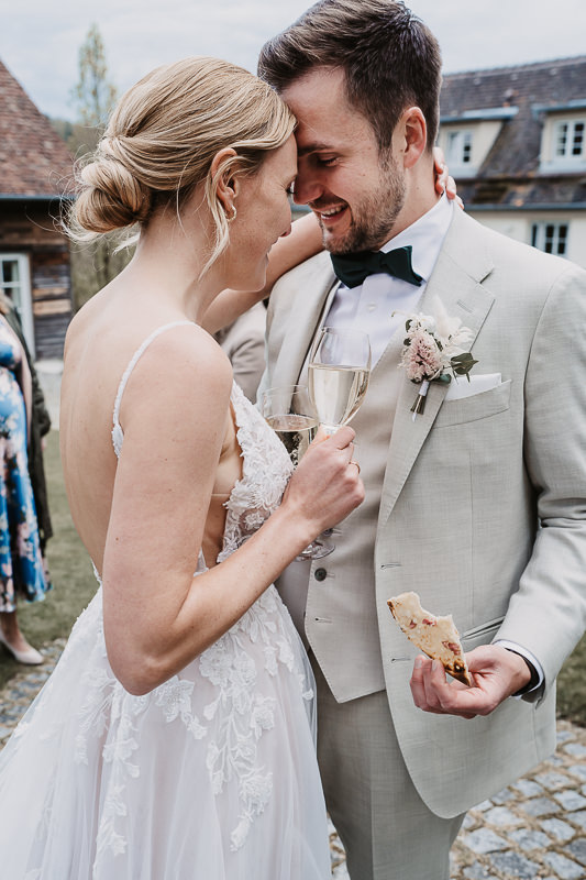 Das Brautpaar lehnt liebevoll die Stirn aneinander, während sie bei ihrer Hochzeit auf der Maisenburg in Ulm anstoßen – fotografiert von Patricia Hamann.