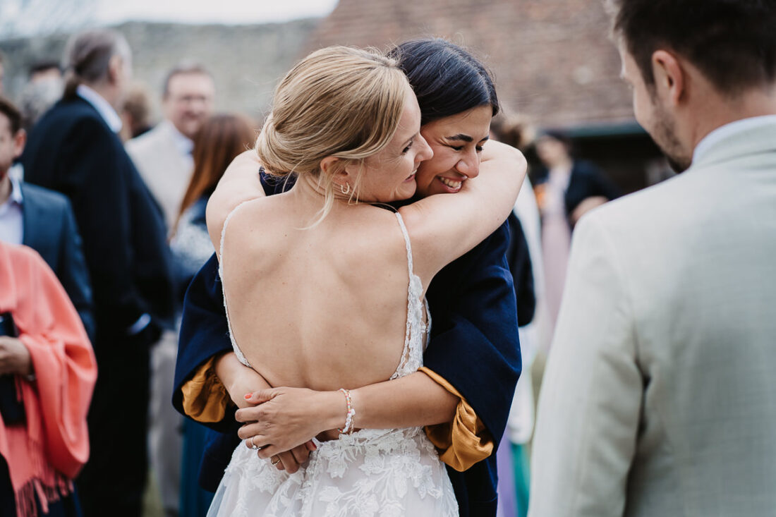 Braut und Freundin umarmen sich herzlich bei einer Sommerhochzeit auf der Maisenburg, fotografiert von Patricia Hamann aus Ulm.