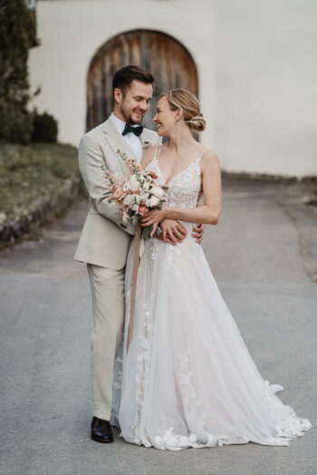 Braut und Bräutigam lachen sich verliebt an, während sie sich auf der Maisenburg bei Ulm umarmen – fotografiert von Patricia Hamann, Hochzeitsfotografin.