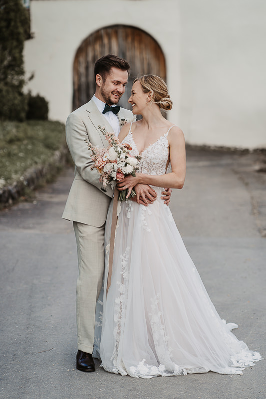 Braut und Bräutigam lachen sich verliebt an, während sie sich auf der Maisenburg bei Ulm umarmen – fotografiert von Patricia Hamann, Hochzeitsfotografin.