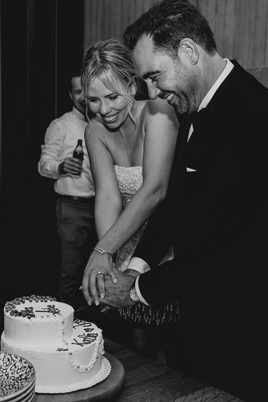 Das Brautpaar schneidet lachend die Hochzeitstorte in der Werft1919 am Bodensee an, fotografiert von Patricia Hamann Hochzeitsfotograf Bodensee