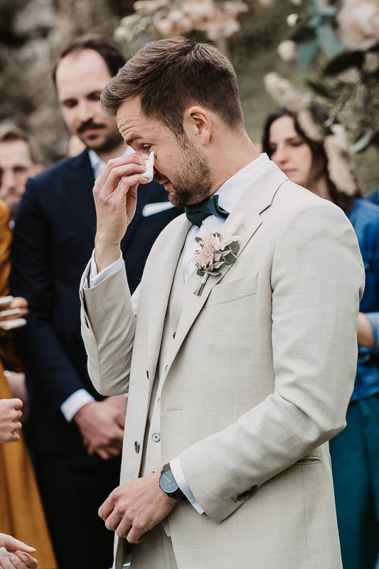 Bräutigam wischt sich während der Trauung auf der Maisenburg eine Träne aus dem Gesicht. Aufnahme von Hochzeitsfotografin Patricia Hamann aus Ulm.