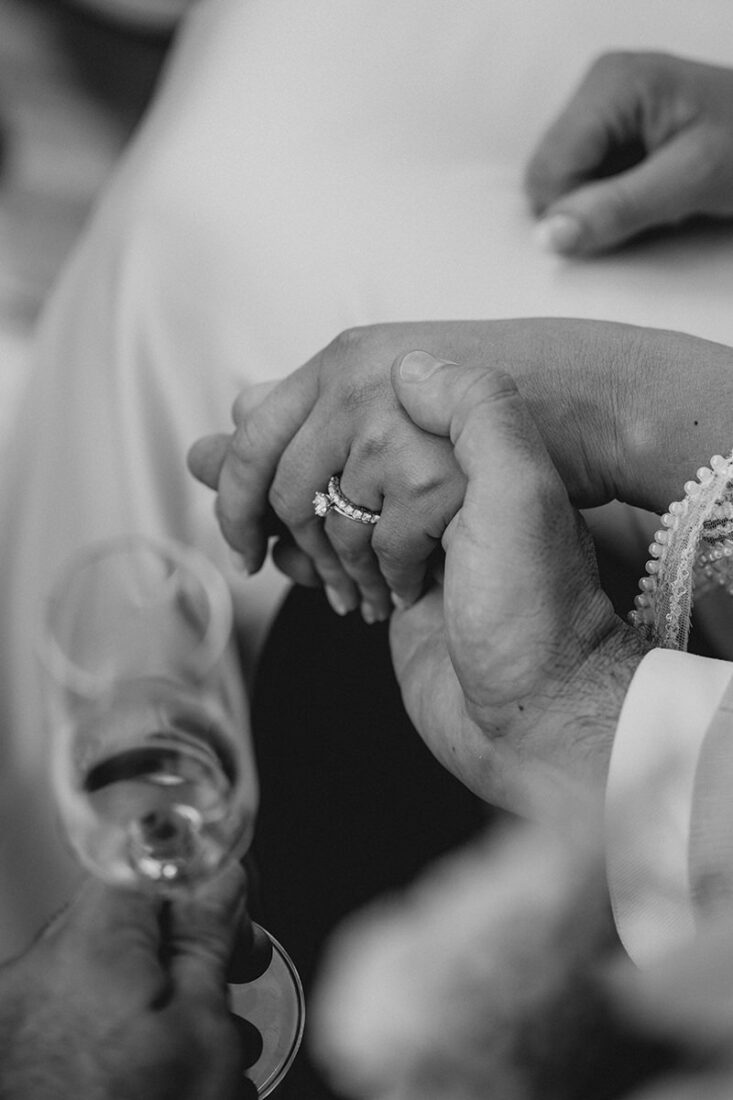 Nahaufnahme bei einer Hochzeit auf Ibiza zweier Hände eines Brautpaares, die sich liebevoll halten, mit funkelndem Ehering.