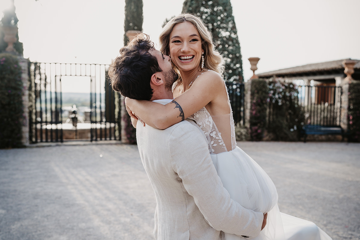 Bei einer Hochzeit auf Ibiza hebt Bräutigam seine Braut in die Luft und küsst sie zärtlich.