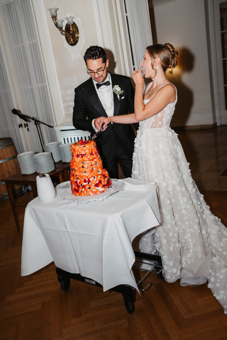 Brautpaar schneidet gemeinsam die Hochzeitstorte im festlichen Saal des Hotel Bad Schachen an.