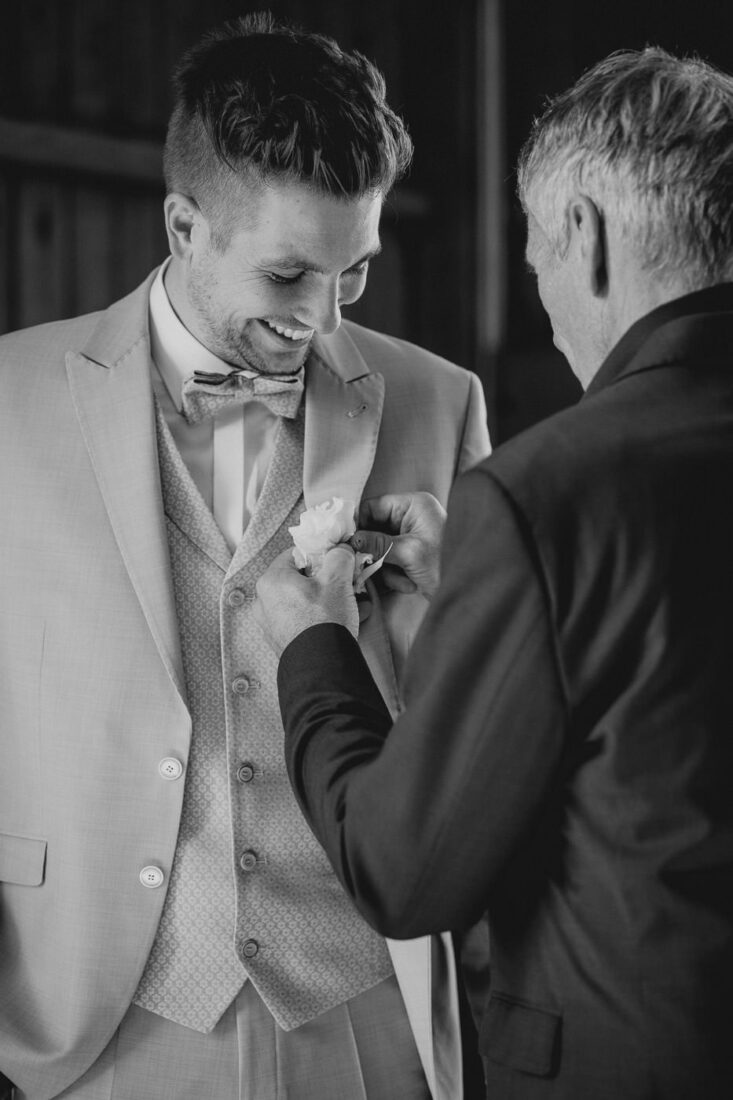 Der Bräutigam bekommt von seinem Vater die Ansteckblume an sein Jacket gesteckt.