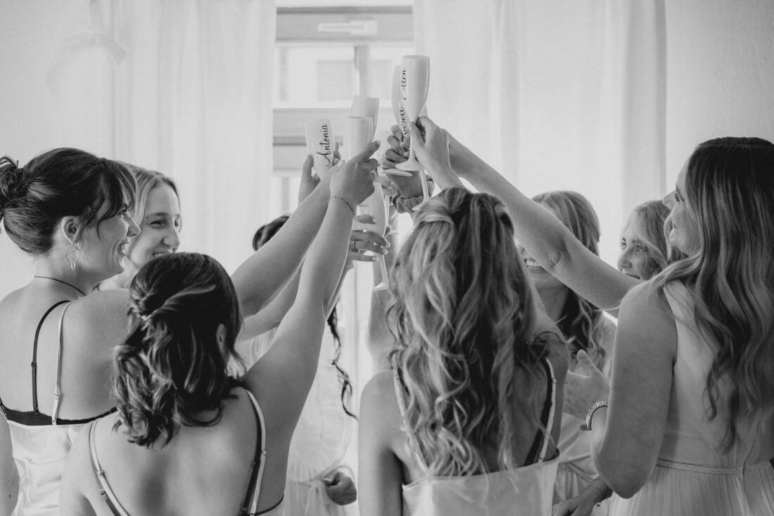 die Braut und ihre Freundinnen zelebrieren das Getting Ready zusammen und stoßen mit Champagnergläsern an.