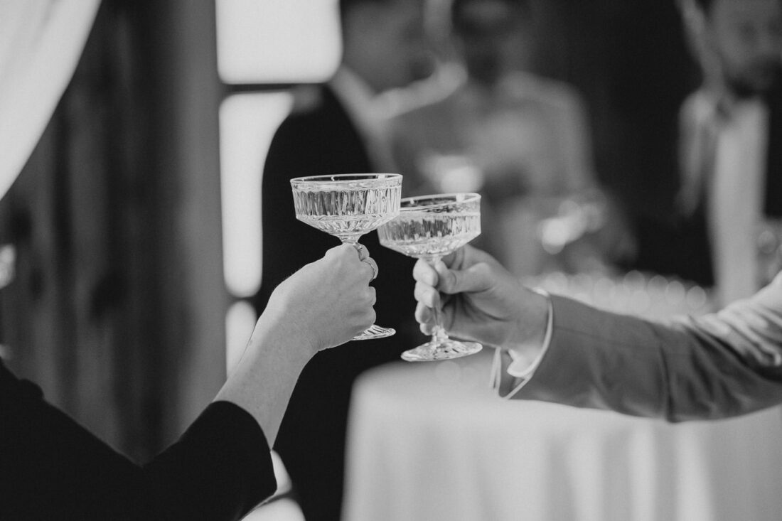 Zwei Gäste stoßen mit eleganten Kristall-Coupés auf das Glück des Brautpaares an.