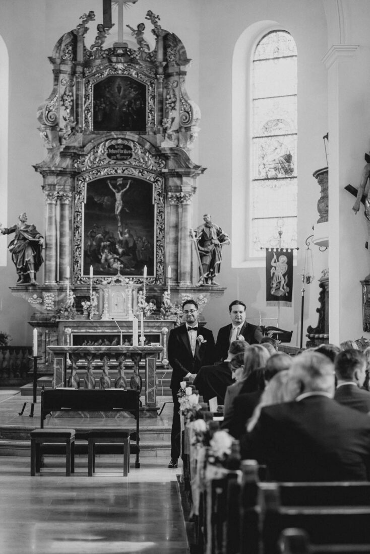 Ein Bräutigam wartet gespannt am Altar einer barocken Kirche in Lindau auf den Einzug der Braut.