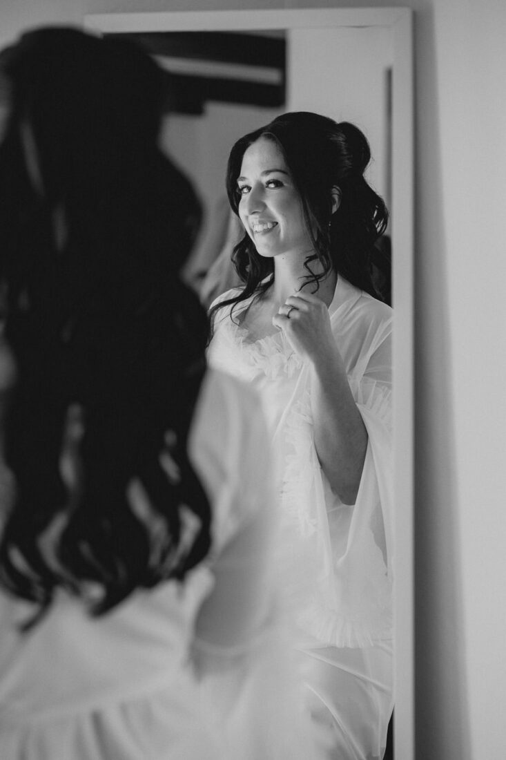 Braut lächelt ihr Spiegelbild an.