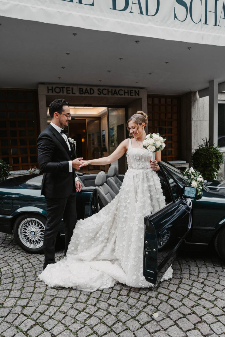 Das Brautpaar kommt an der Hochzeitslocation im Hotel Bad Schachen an und steigt aus dem Cabrio.