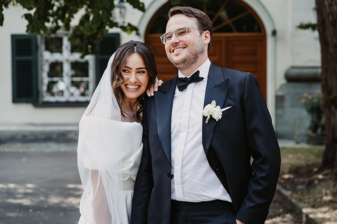 Brautpaar lacht glücklich vor dem Schloss in Friedrichshafen.