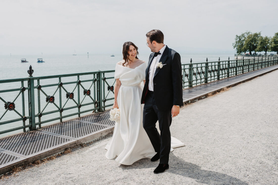 Brautpaar spaziert lachend an der Uferpromenade in Friedrichshafen am Bodensee entlang.