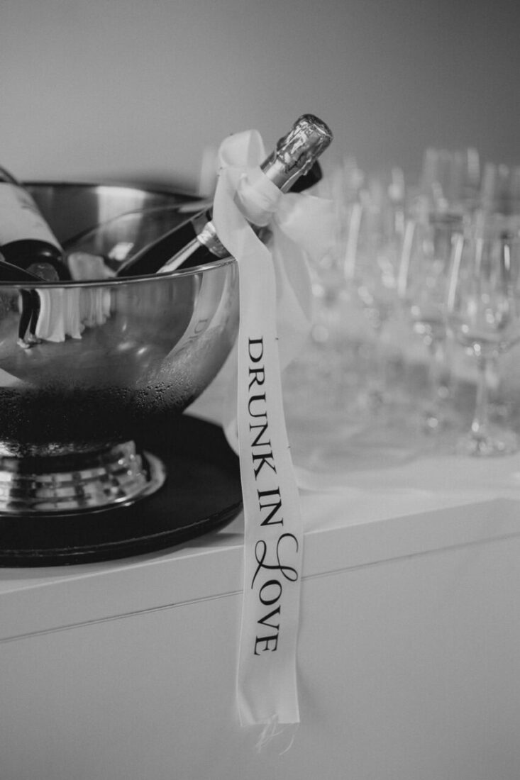 Champagnerflaschen im Eiskübel mit einer Schleife „Drunk in Love“ in Schwarz-Weiß.