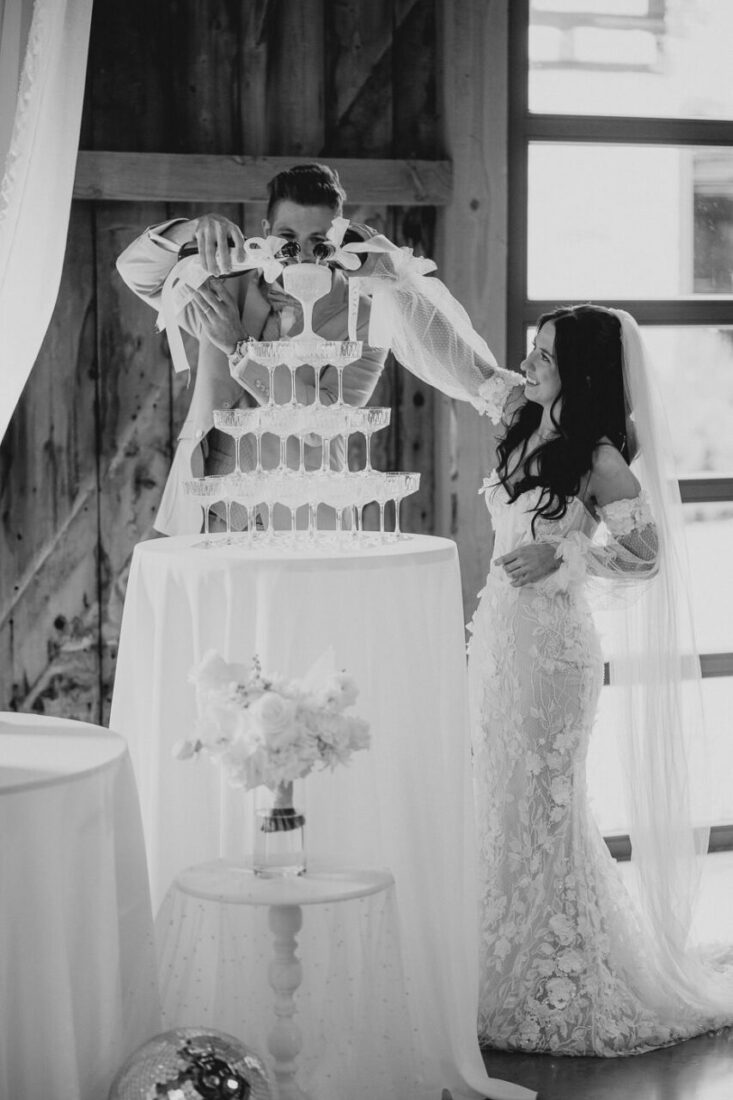 Das Brautpaar füllt gemeinsam die obersten Gläser der beeindruckenden Champagner-Pyramide.