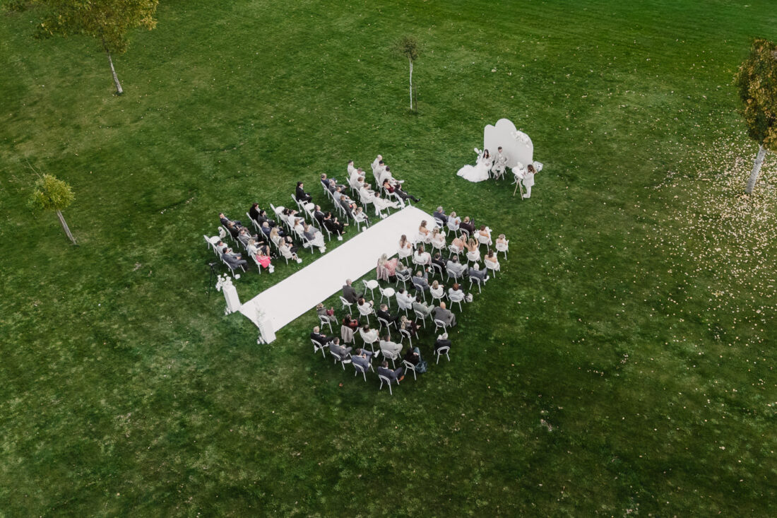 Luftaufnahme der freien Trauung auf der großen Wiese des Steinbachhofs mit Blick auf die Gäste und das Brautpaar.