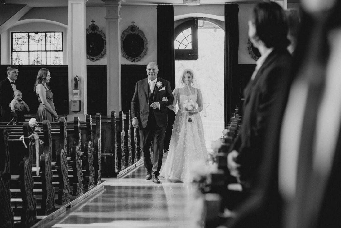 Braut und Vater schreiten gemeinsam durch den Mittelgang der Kirche in Lindau-Reutin.