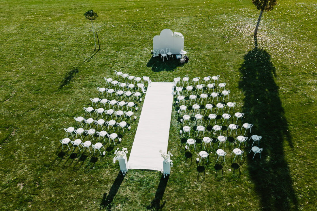 Drohnenfoto der aufgebauten weißen Stühle für eine freie Trauung auf der grünen Wiese am Steinbachhof.