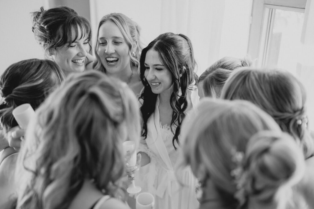 Die Braut und ihre Brautjungfern umarmen sich alle beim Getting Ready und lachen dabei.