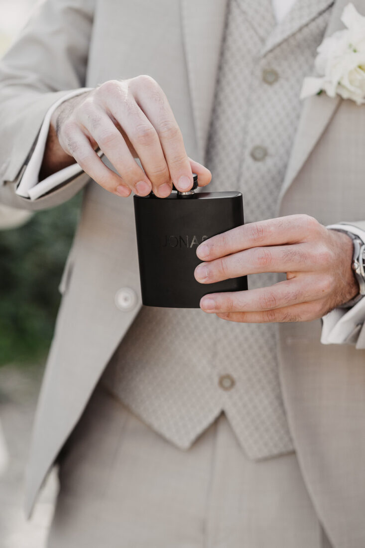 Der Bräutigam öffnet einen gravierten Flachmann