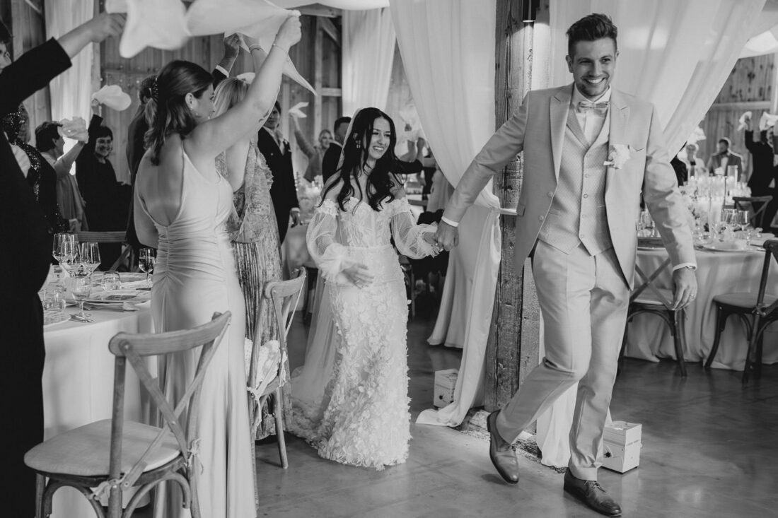 Gäste schwenken weiße Servietten zum Takt der Musik, während das Brautpaar durch die Reihen tanzt.