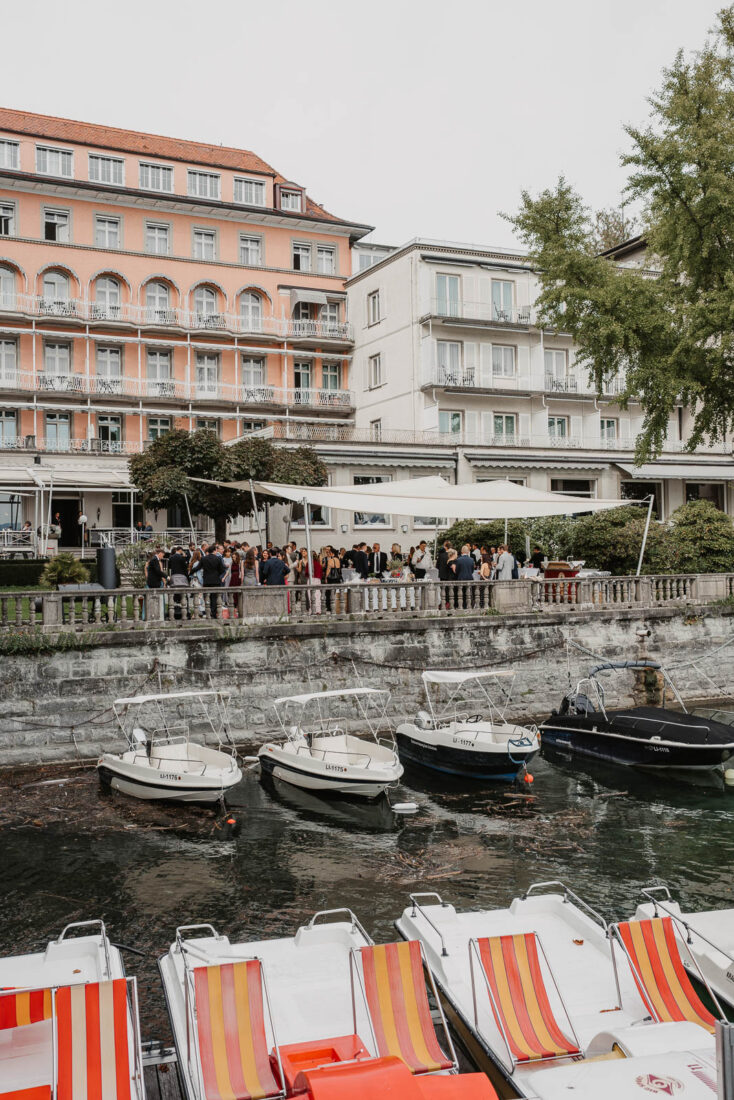Hochzeitsgesellschaft beim Sektempfang auf der Terrasse des Hotel Bad Schachen in Lindau direkt am Bodensee-Ufer mit Booten.