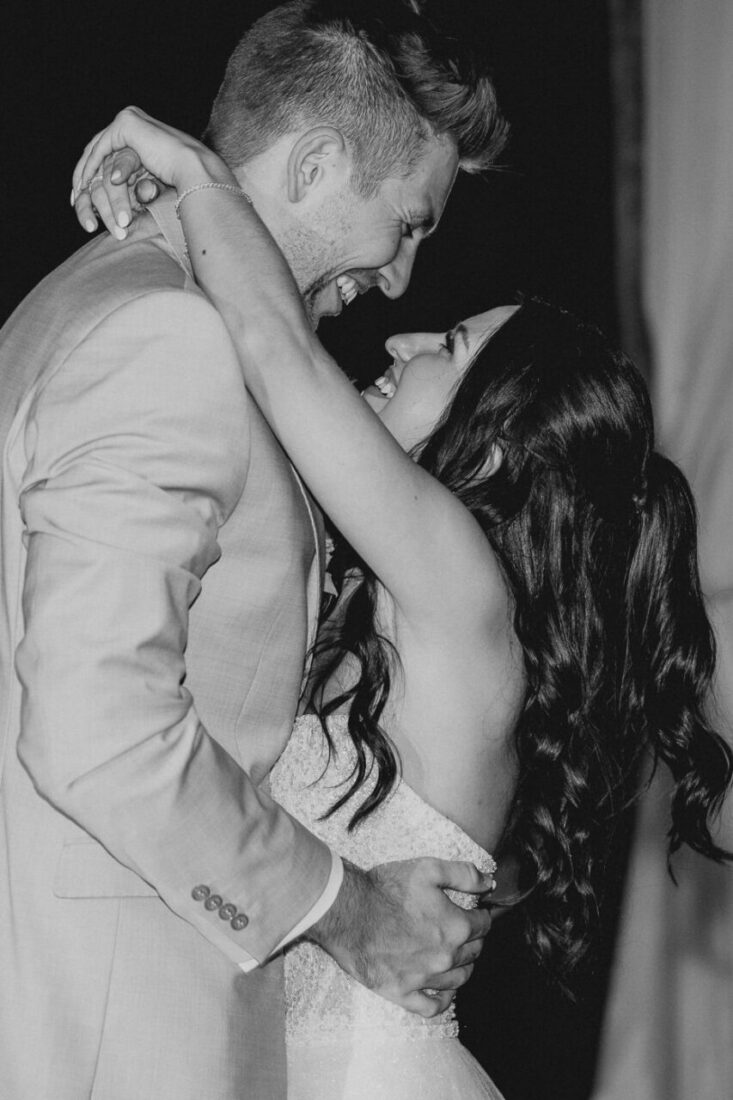 Braut und Bräutigam umarmen sich innig und lachen sich verliebt an.