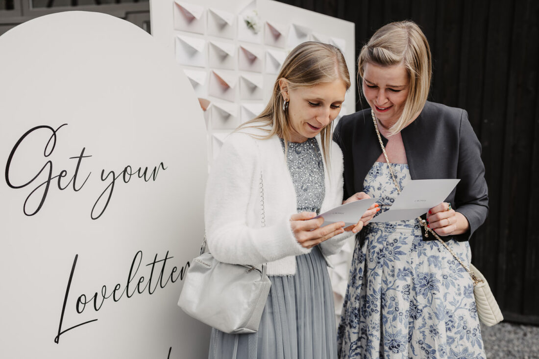 Hochzeitsgäste lesen persönliche Briefe an einer "Loveletter"-Station auf dem Steinbachhof.