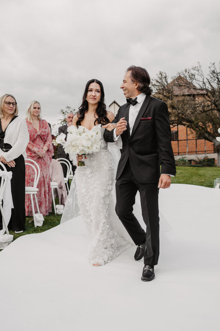 Braut zieht mit Brautvater zur Trauung auf dem Steinbachhof ein, begleitet von den Blicken der Gäste.