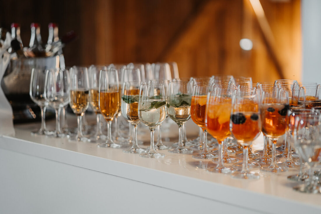 Lange Reihe mit Aperol Spritz und Sektgläsern auf einem weißen Tresen für die Hochzeitsgesellschaft.