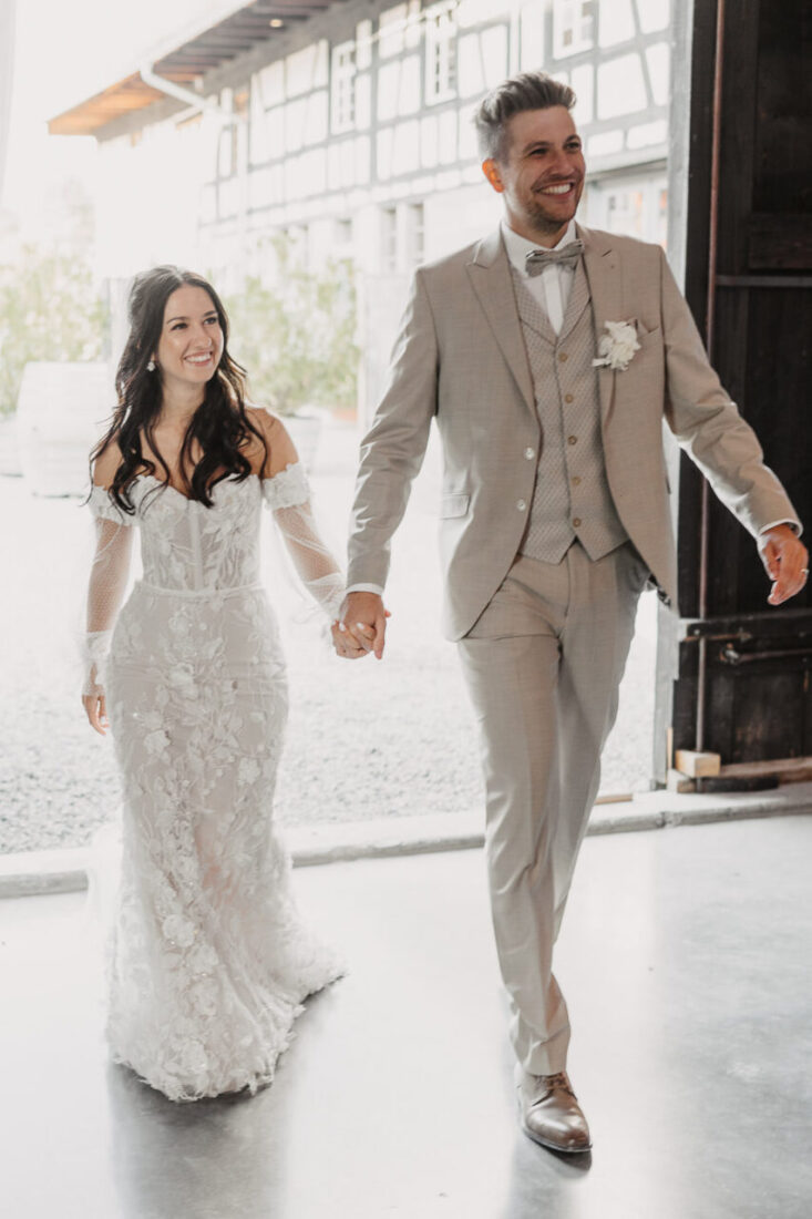 Das strahlende Brautpaar zieht unter Applaus der Gäste in die festlich dekorierte Scheune ein.