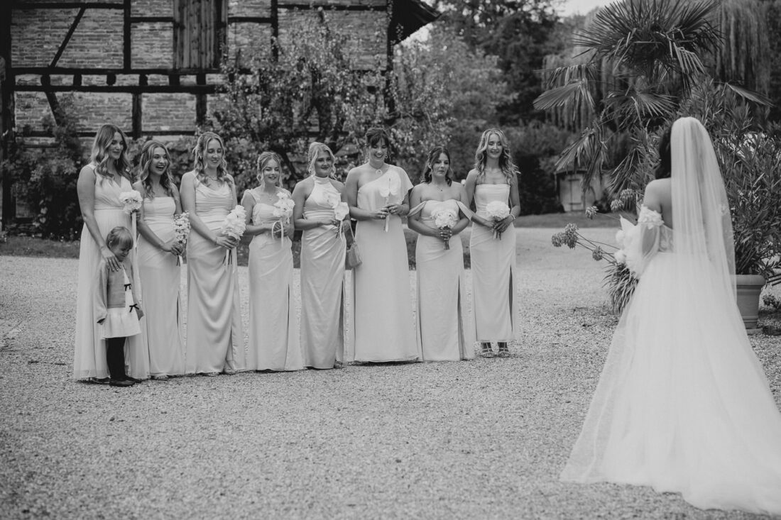 Brautjungfern in einer Reihe erwarten die Braut zum First Look vor der Kulisse des Steinbachhofs.