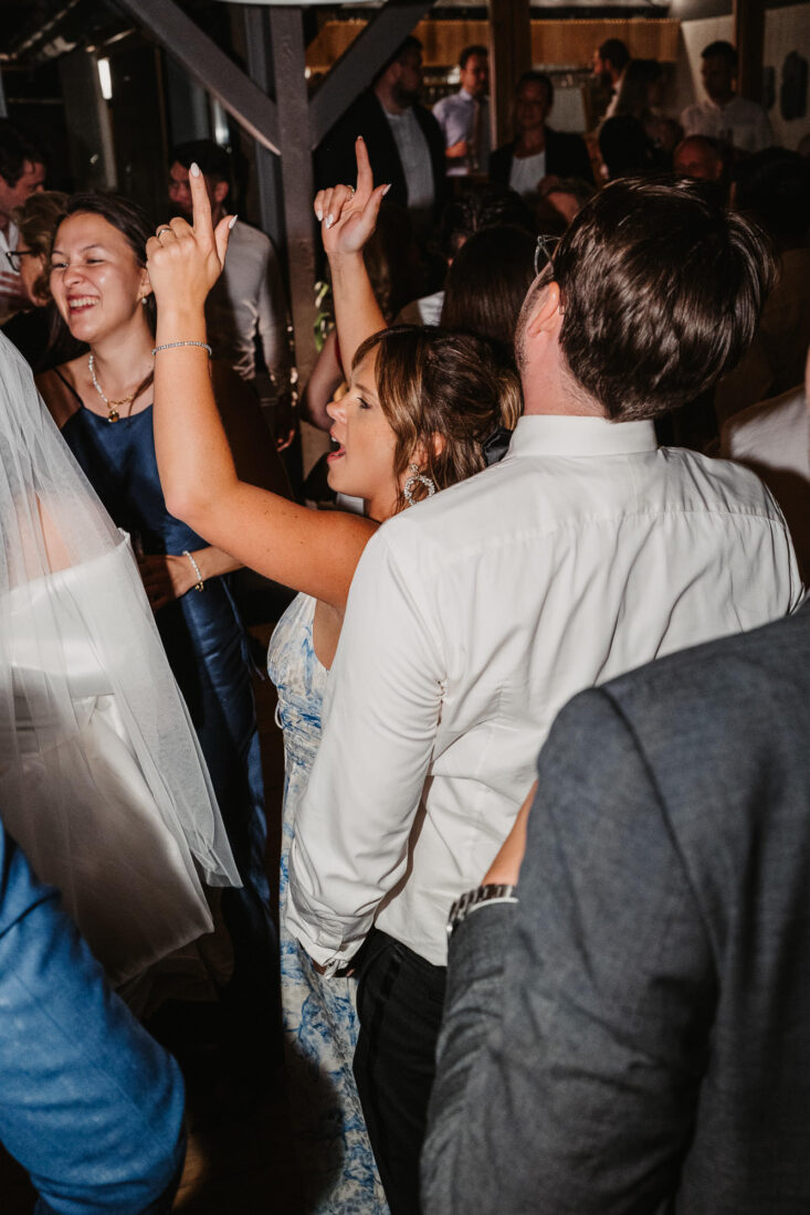 Hochzeitsgäste feiern ausgelassen mit erhobenen Händen bei der Hochzeitsfeier nahe Friedrichshafen.