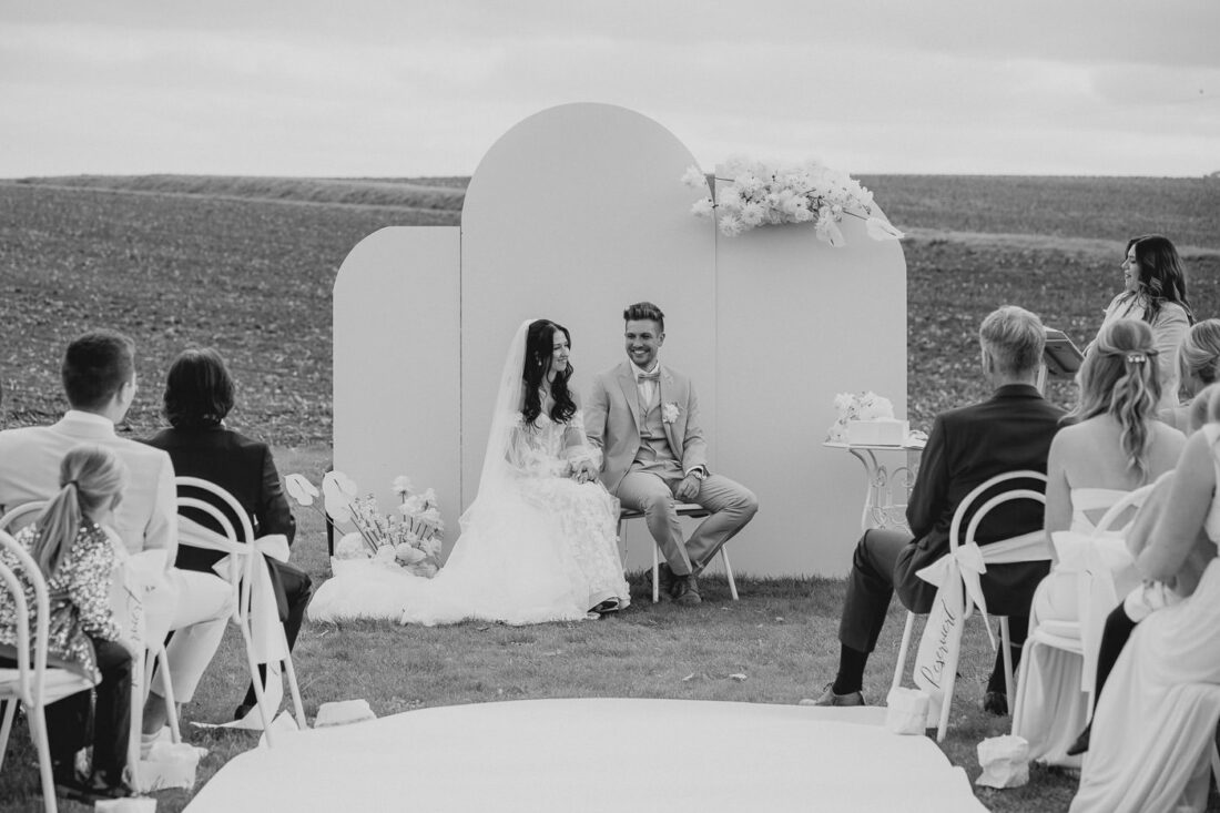 Weite schwarz-weiß Ansicht der freien Trauung auf dem Außengelände des Steinbachhofs mit Blick auf die Felder.
