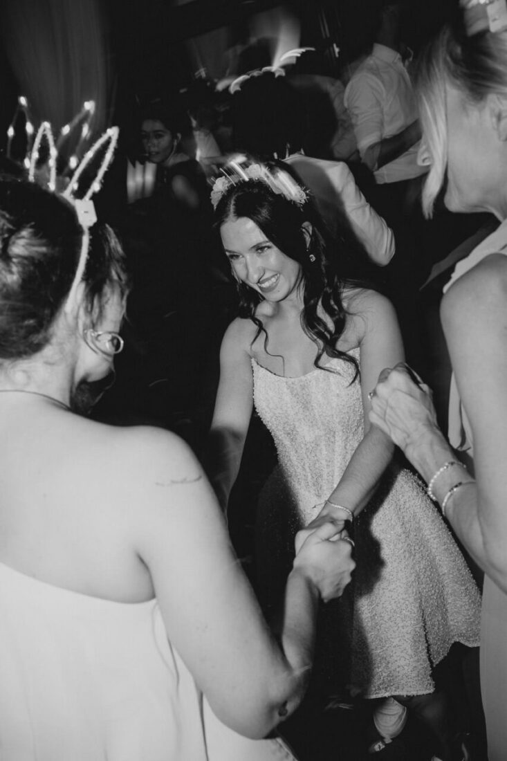 Die Braut tanzt ausgelassen inmitten ihrer Trauzeuginnen bei ihrer Hochzeitsparty auf dem Steinbachhof.